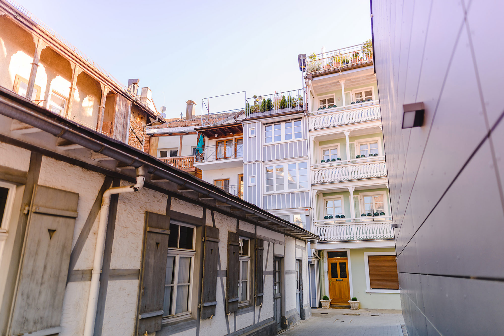 Blick in einen Innenhof mit traditionellen und modernen Gebäuden, hellblauer Himmel im Hintergrund.