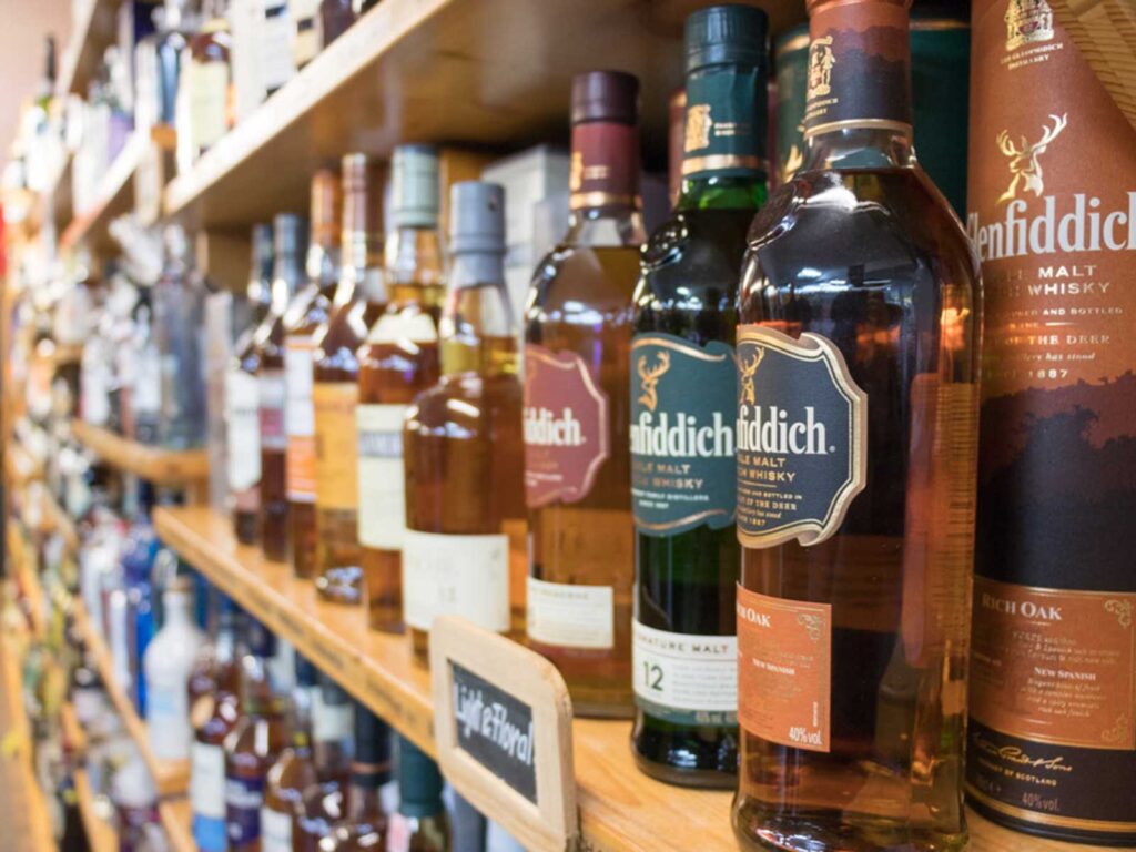 Regalbrett mit verschiedenen Whisky-Flaschen, darunter Glenfiddich, in einer Spirituosenhandlung.