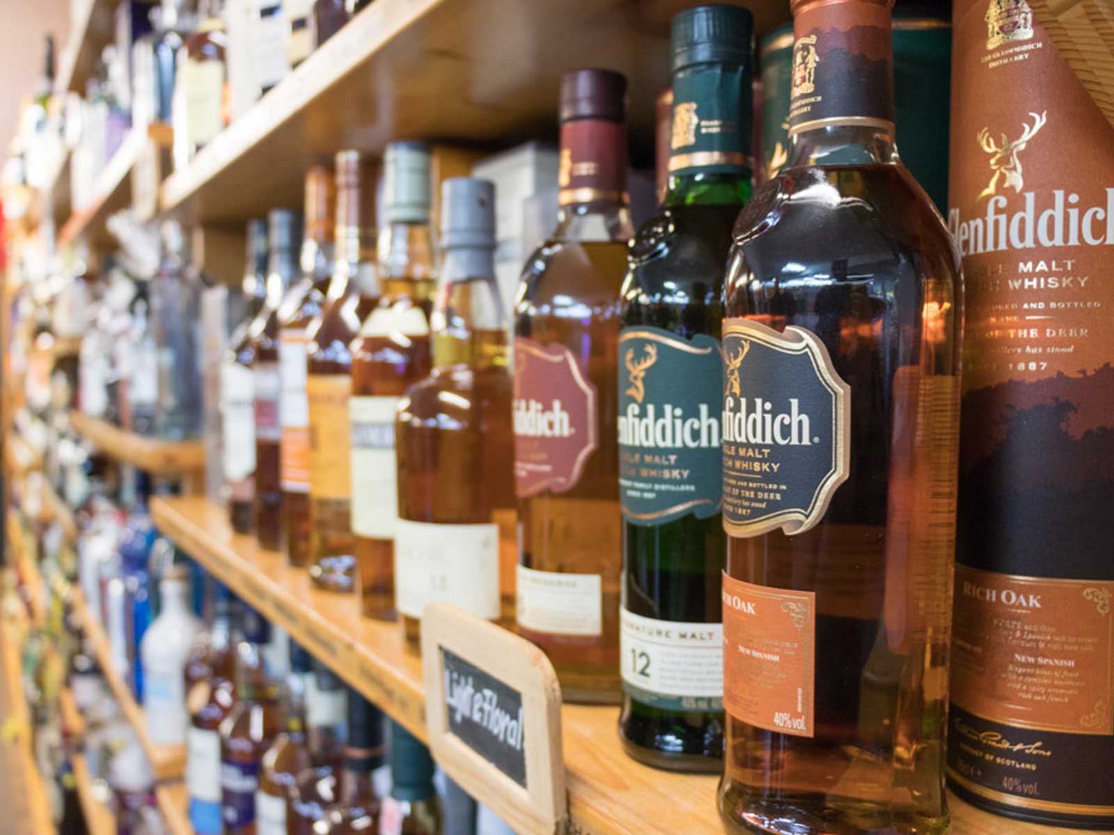 Regalbrett mit verschiedenen Whisky-Flaschen, darunter Glenfiddich, in einer Spirituosenhandlung.