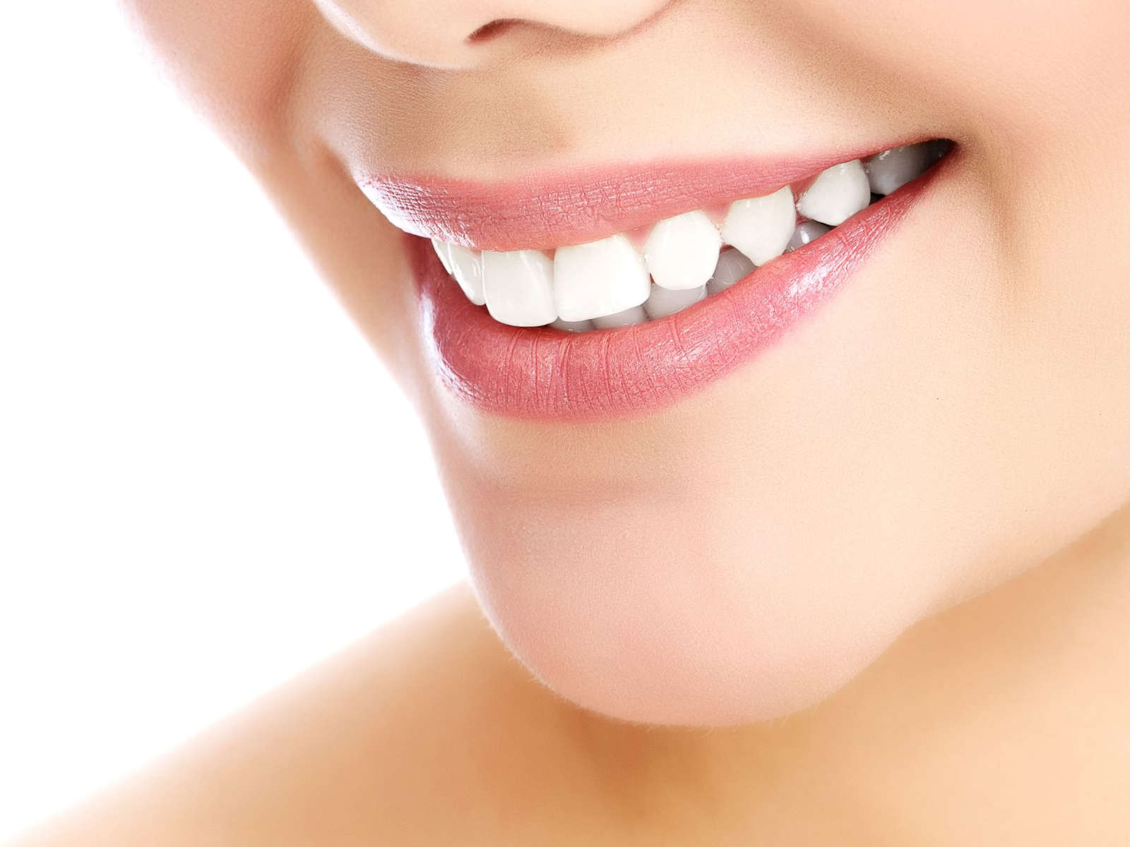 Nahaufnahme eines lächelnden Gesichts mit weißen, strahlenden Zähnen und sanfter Lippenfarbe.