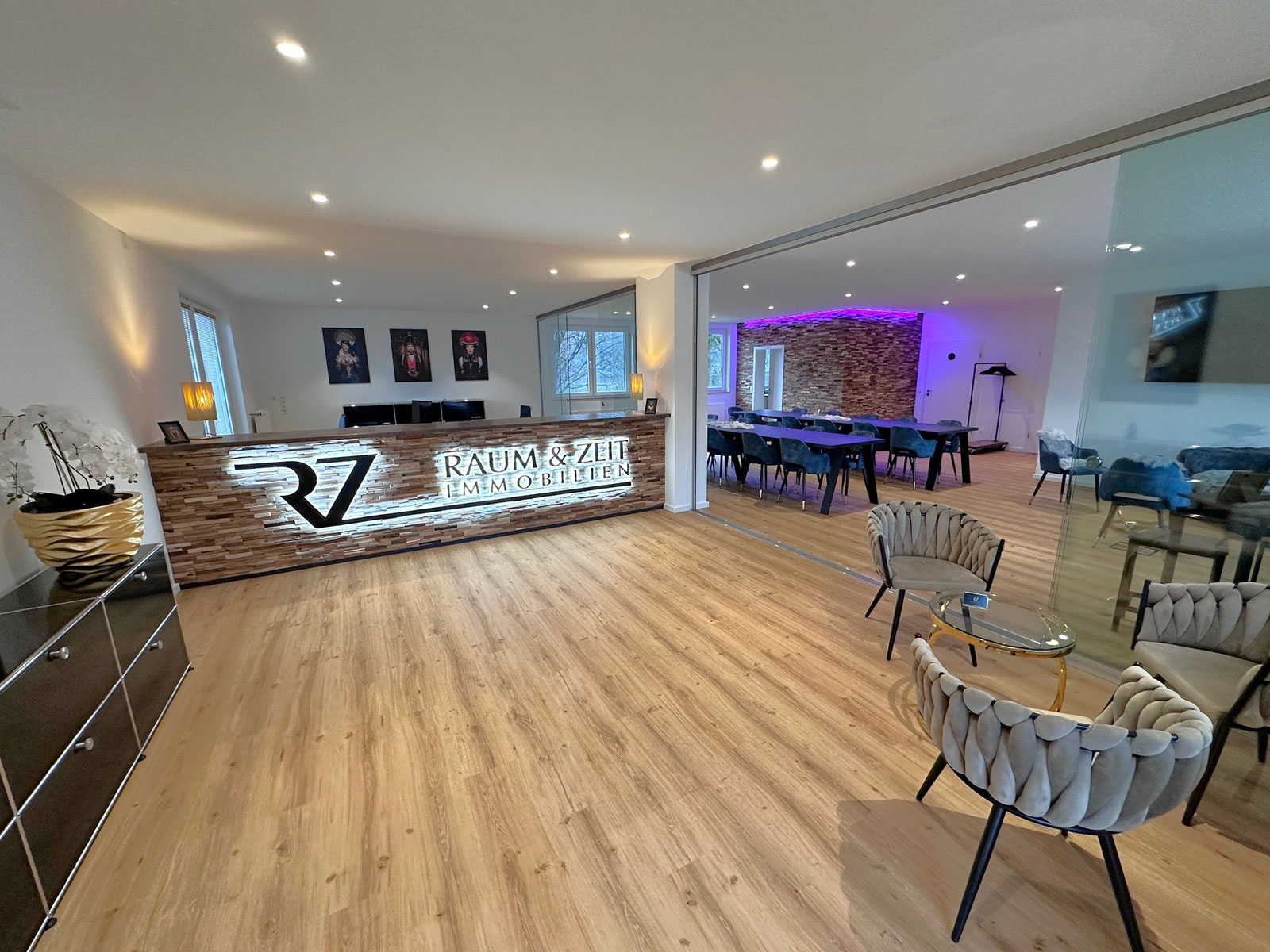 Moderne Empfangshalle mit schickem Empfangstresen und eleganten Sitzbereichen. Heller Raum mit Holzfußboden und Kunstwerken.