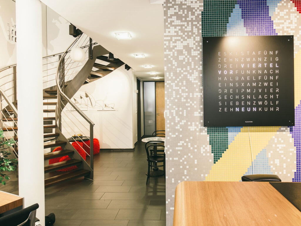 Moderne Bürogestaltung mit einer eleganten Wendeltreppe und einer bunten Wandinstallation.