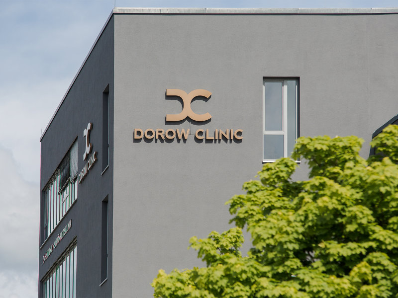 Das Bild zeigt die Fassade der Dorow Klinik mit einem modernen, grauen Gebäude und einer Pflanze im Vordergrund.