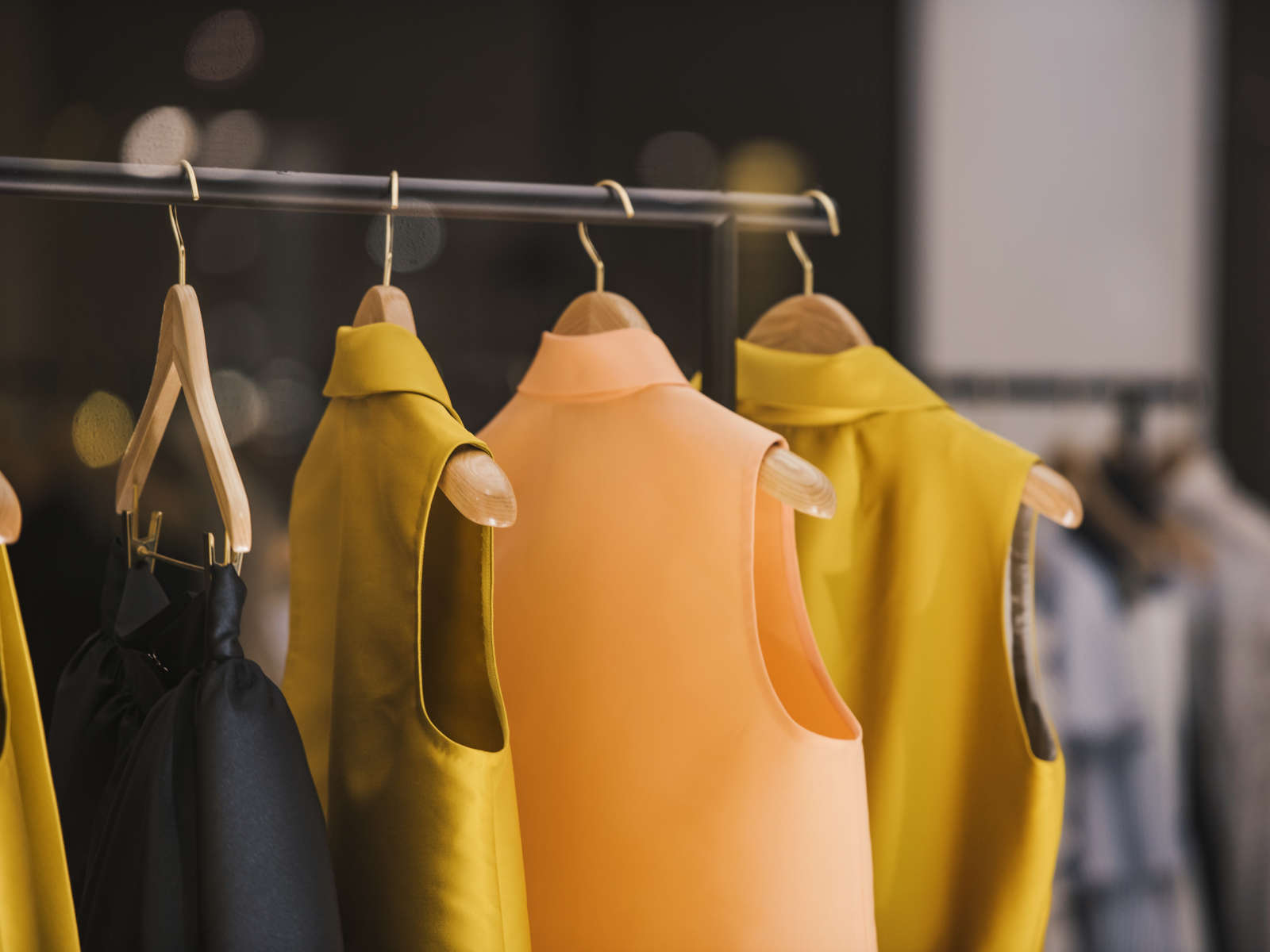 Kleider in verschiedenen Farben hängen an einem Kleiderständer, beleuchtet von einem sanften Licht.