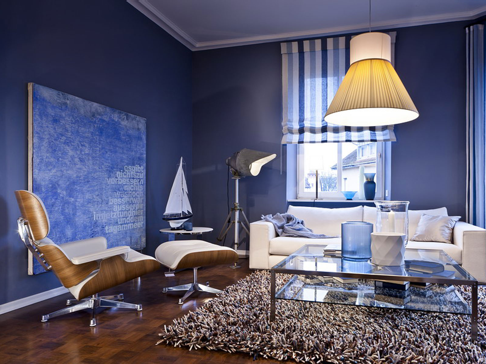 Moderne Wohnzimmergestaltung mit blauen Wänden, Designer-Möbeln, einem Teppich und Dekorationselementen.